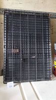 Flat stacked wire metal panels of a medium size black dog crate showing crisscross wire pattern and hinges