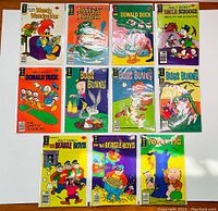 Photo showing the full lot of 11 vintage cartoon comic books from Gold Key Comics featuring popular characters like Woody Woodpecker, Daffy Duck, Donald Duck, Uncle Scrooge, Bugs Bunny, The Beagle Boys, and Porky Pig.