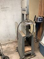 Full view of band saw and stand in basement setting