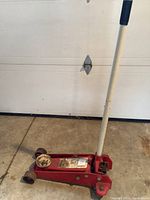 Side view of the red hydraulic floor car jack showing the handle and lifting saddle