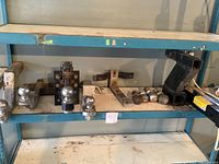 Wide view of assorted ball hitches and hitch balls on a steel shelf, showing multiple mounting brackets and several ball hitch components.