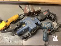 Metal bench vise, Craftsman paint peeler, Black & Decker corded drill, Mastercraft belt sander, and yellow DeWalt angle grinder on workbench.