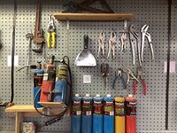 Full view of assorted hand tools hanging on pegboard including locking pliers, yellow-handled cutters, clamps, putty knife, and 6 Bernzomatic fuel canisters.