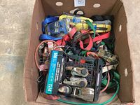 Photo of the box containing assorted ratchet tie downs and bungee cords showing a variety of colors and types.