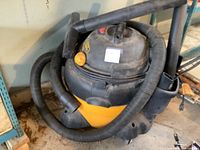 Overall view of Shop Vac wet/dry vacuum on floor showing hose wrapped around unit and handle on top.