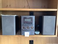Sony stereo system CMT-M70 with two speakers and remote on wooden shelving