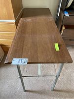 Top angled view of folding table showing wooden top surface with scratches and metal legs.