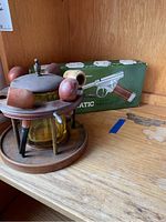 Photo of vintage wooden pipe rack with glass match holder and boxed gas-powered match lighter in background