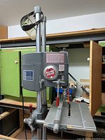 Frontal view of Shop Smith machine showing rotating attachment dial, table and drill head