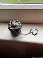 Front view showing perforated surface and chain with ring attached