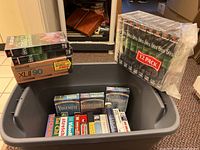 Full lot overview with open tub showing various VHS tapes including travel, exercise, and Maxell cassettes.