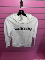 Front view of white Adidas hoodie with logo text on front and hood with drawstrings.
