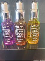 Three unopened Moira branded facial serums in glass dropper bottles: Peptide Enzyme Energy, Collagen Retinol Treatment, and Propolis Chamomile Rejuvenating.