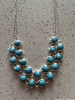 Close-up of the silver necklace showing the blue stones in detail and the setting.