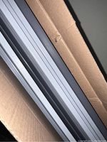8 foot slatwall panel inside cardboard box, showing horizontal grooves and metallic surface.