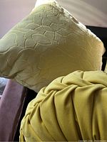 Close-up of square and round yellow pillows showing different fabric textures and designs.
