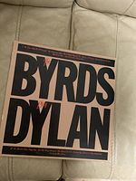 Photo of the album cover showing the title 'The Byrds Play Dylan' with large black letters on cream background.