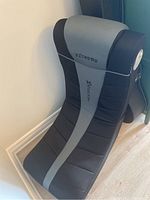 Full angled view of the ExtremeX Rocker gaming chair showing padded seat and backrest with brand logos and speakers on sides.