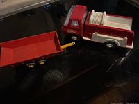Photo showing red and white vintage Tonka truck connected to red Matchbox trailer with yellow hitch.