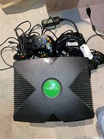 Top view of original Xbox console with multiple wired controllers around it.