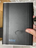 Front view of the black Lizone Extra Pro Series external battery showing logo and overall design.