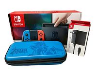 Front view showing Nintendo Switch console box with neon Joy-Cons, separate AC adapter box, and Legend of Zelda carrying case.