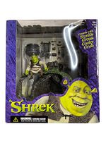 Front view of the complete boxed Shrek's Swamp House playset showing the figure, swamp house structure, and packaged accessories.