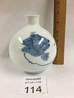 Front and side view of the round white porcelain vase with blue floral design and a ruler for size reference showing approximately 5.5 inches height.