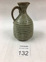 Frontal view of the textured ceramic jug with handle and spout, showing the patterned glaze and form.