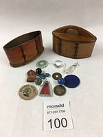Small wooden oval boxes with assorted vintage pins, buttons, and decorative items arranged in front, showing condition and variety of contents.