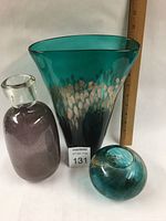 Set of three vases: tall flared teal vase with beige/black design, small round teal vase, clear cylindrical vase with dark purple interior