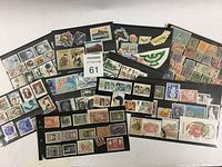Top view of various stamps on black album pages showing multiple countries and stamp designs