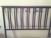 Photo of brown metal queen sized bed headboard showing vertical bars and mounting points.