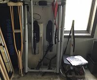 Photo showing Total Gym 1000 machine, wooden crutches, and other exercise equipment in storage area near window.