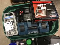 Top view of green tub containing various tools including boxed Craftsman jigsaw, Mastercraft socket set case, small gray drill bit case, green screwdriver, and assorted tools.