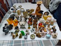 Overview of assorted candle holders and small decorative ornaments arranged on a table, showing various styles and materials.