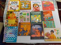 Top-down view of 13 craft and science books arranged in a grid on a white surface.