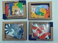 Four wooden animal puzzles in original packaging featuring fox, raccoon, snail and elephant designs with numbered pieces.
