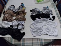 Lot of nine bras arranged on a table showing color and pattern variety including leopard print, snake print, black, and white. Bras appear new with tags.