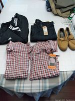 Photo showing the two Kirkland XXL plaid shirts, Adidas black jacket, Levi jeans, and tan moccasin shoes.