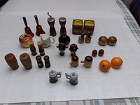 Top down view of 22 assorted vintage salt and pepper shakers arranged on a white cloth.