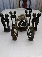 Seven soapstone statues displayed together on a table showing size and shape variety
