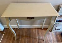Front-facing top view of cream wooden accent table showing top surface and curved legs.