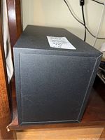 Side view of one speaker, showing black finish and minor surface marks.