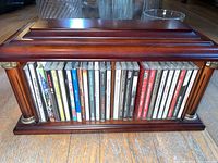 Wooden CD holder filled with CDs visible by their spines showing classical and jazz music genres.