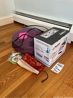 Foot massager circular purple with power cord, red jewelry roll, Podler nail stations box, and fabric pouches on wood floor.