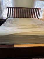 Front view of wooden king size bed frame with vertical slat headboard and mattress on top.