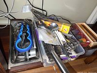 Photo showing a container with multiple kitchen utensils including whisks, apple slicer, garlic press, ladles, and cutlery.