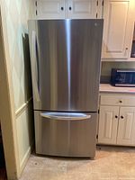 Front view of stainless steel refrigerator showing single-door upper compartment and pull-out freezer drawer.