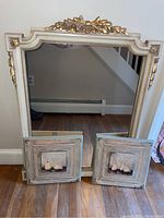 Photo of the framed mirror propped against a wall with the two pear paintings in front, showing overall appearance and relative sizes.